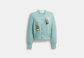 COACH® Women's Cárdigan Con Personajes De Peluche De Algodón Orgánico Coach | Brain Dead en Verde, Talla Mediano