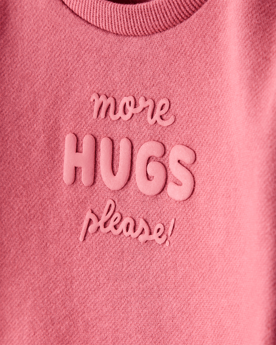 Sudadera rosa con mensaje “More Hugs Please”